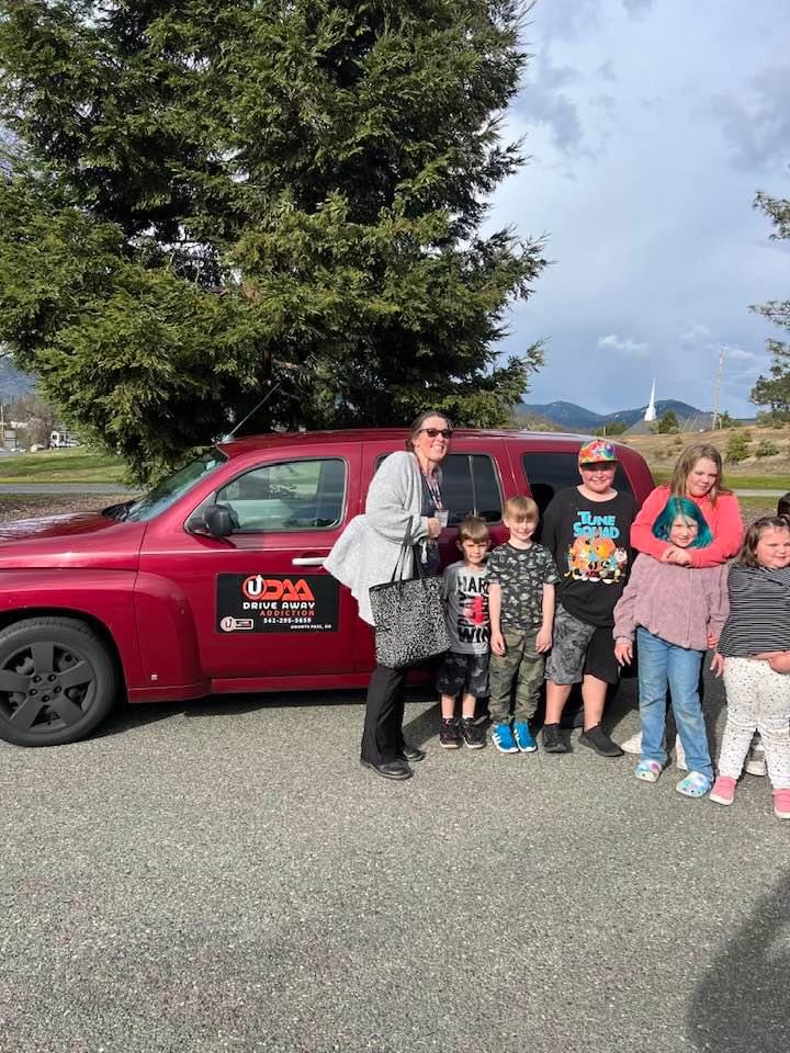 A family beside a red U-Turn ministry vehicle